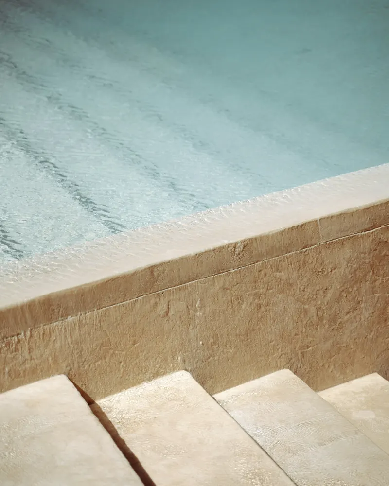 Example of a white plaster pool finish on wide steps with clear water
